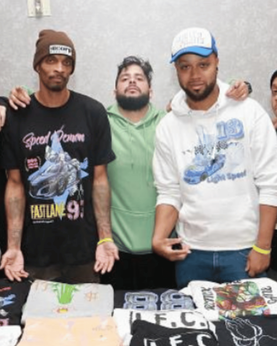 Some of the members of the Remix'd Prints team gather together around a table of their merchandise.