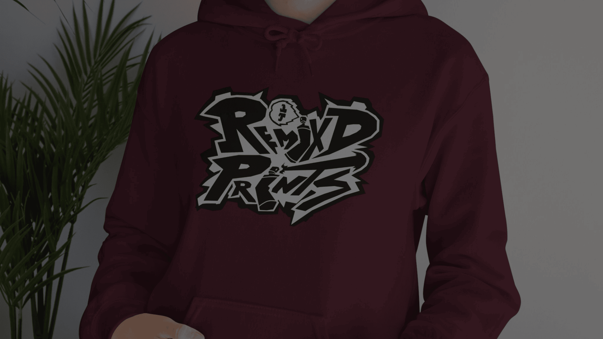 Model wearing a burgundy hoodie featuring a bold black-and-white Remix’d Prints graffiti-style logo on the front.
